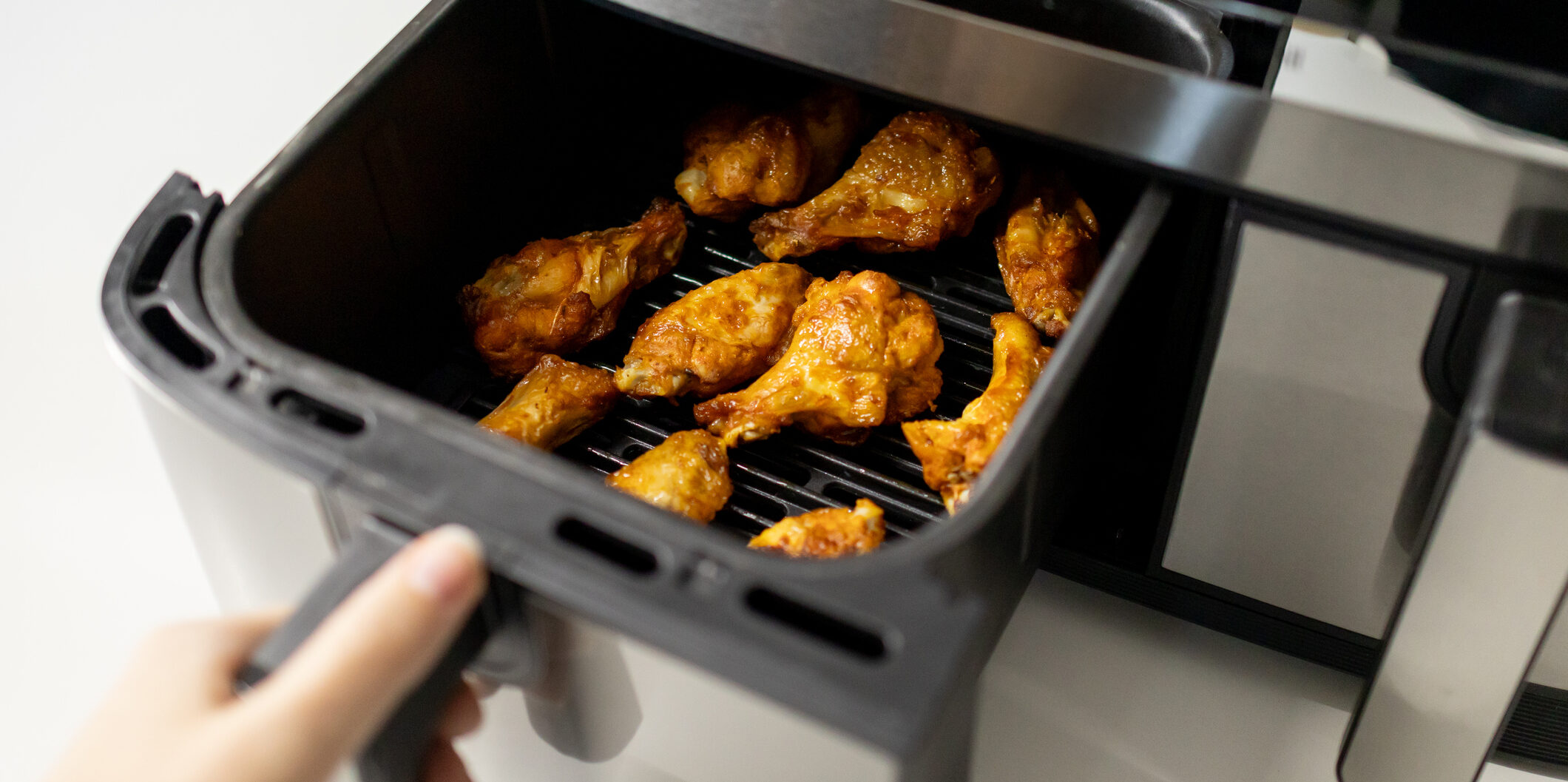 Close-up of chicken wings cooked in an air fryer at the kitchen.